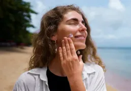 Mulher aplicando protetor solar no rosto ao ar livre